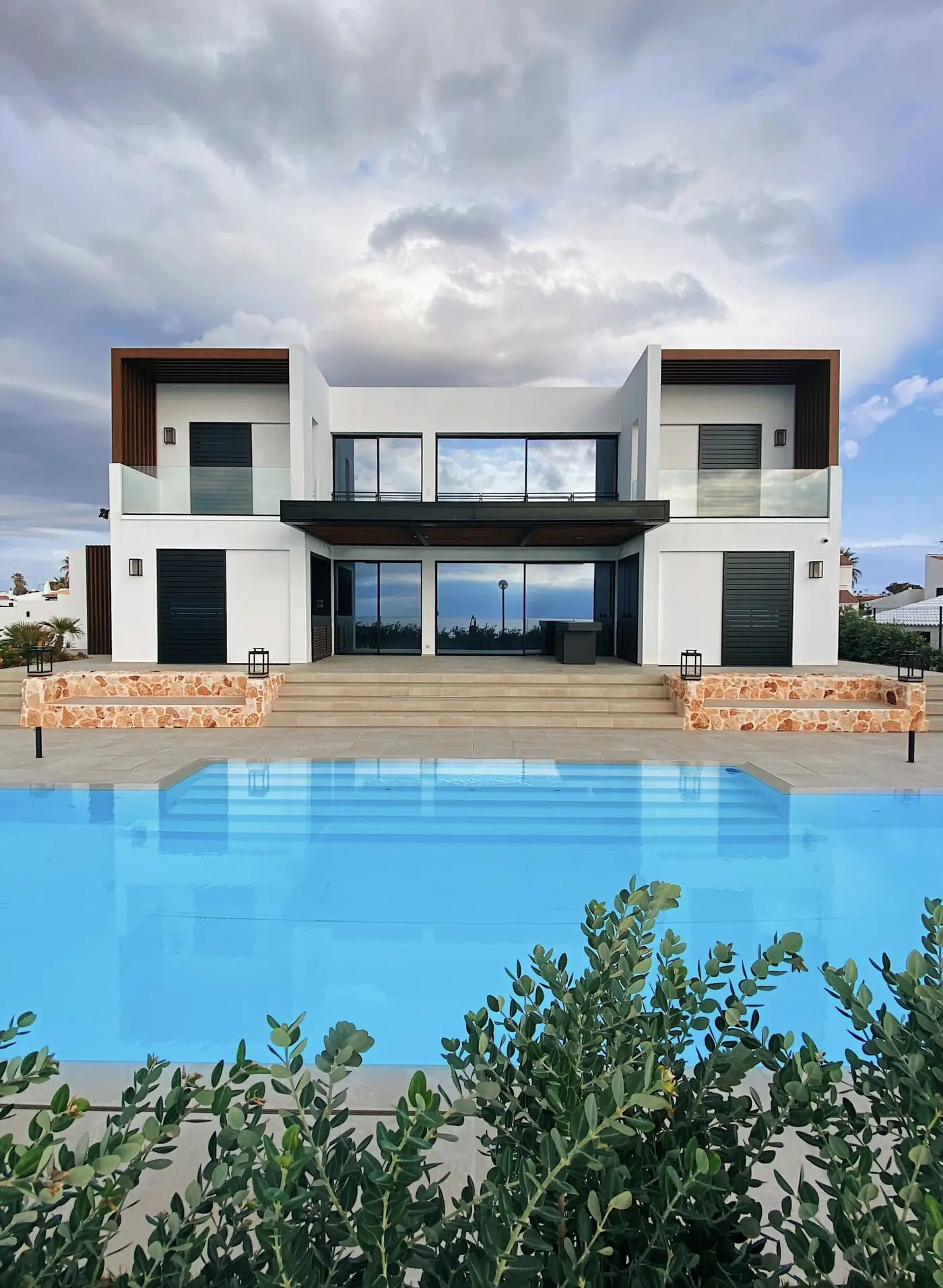 Terrace House: a white two-storey house with timber details behind a long pool