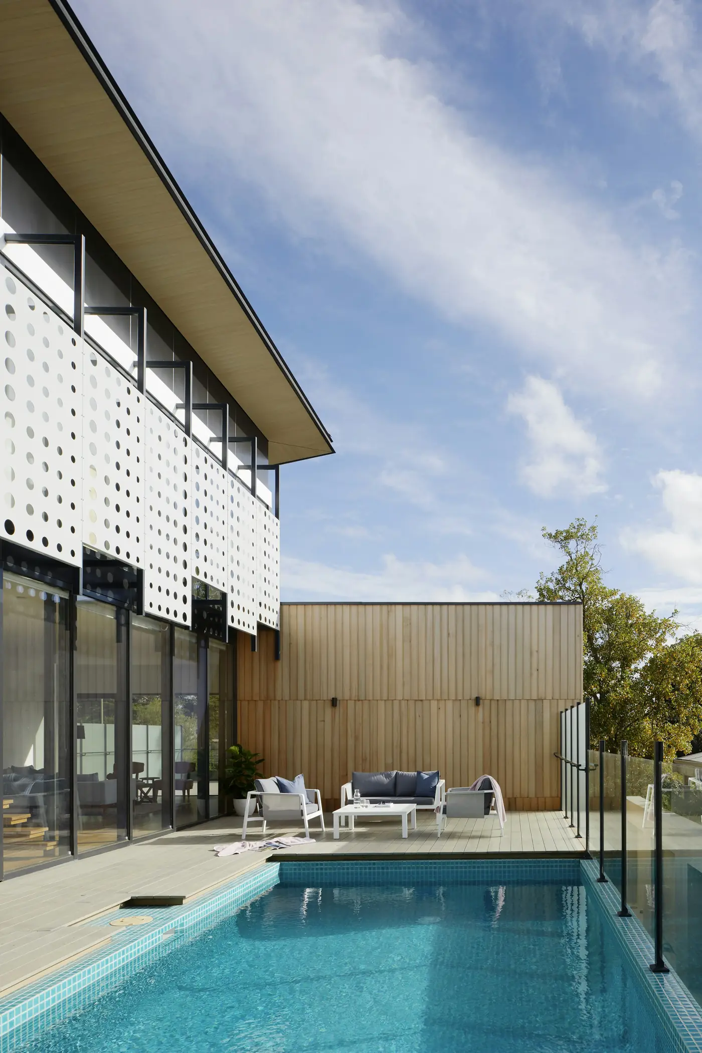 Lattice House: a perforated white screen over a glass facade and a narrow pool