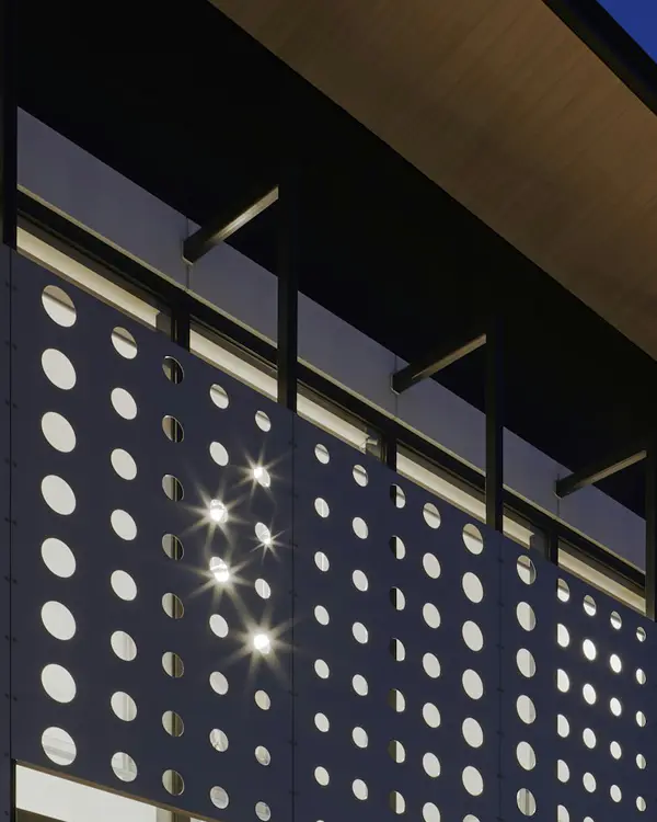 Perforated aluminium screen with lights glowing behind it