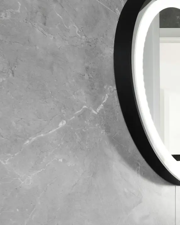 Honed grey stone wall beside a black steel mirror frame