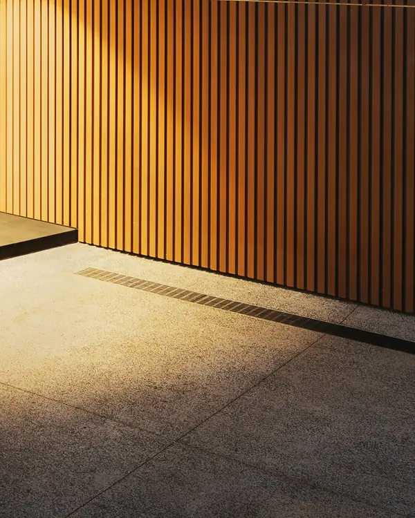 Vertical timber battens lit warm beside an entrance