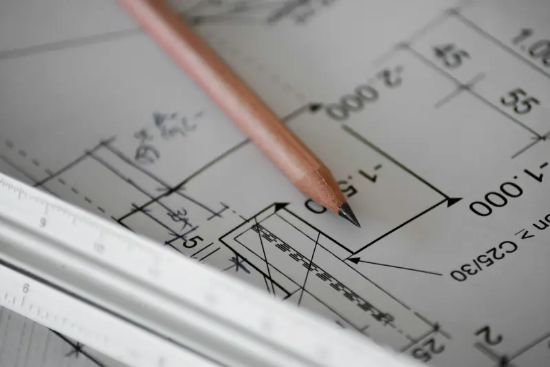 A pencil resting on a dimensioned architectural drawing